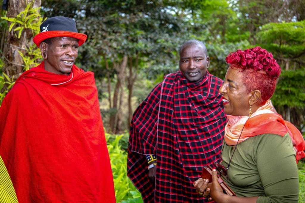 Mama Zara speaking with Maasai men dressed in traditional attire during a cultural visit.