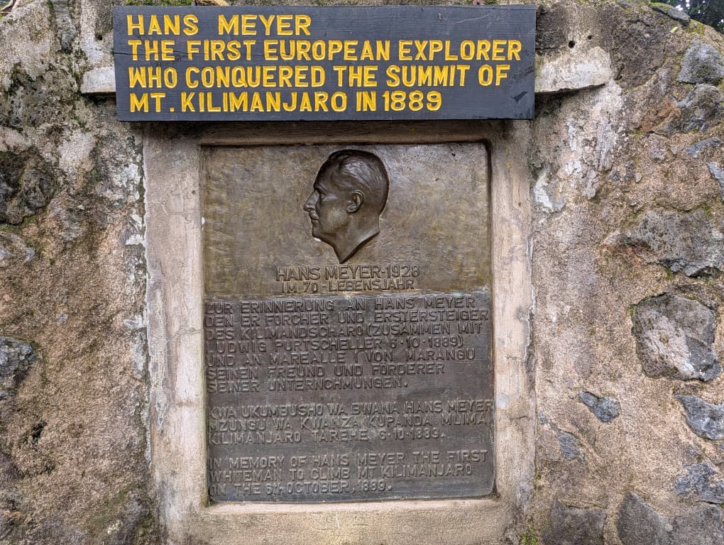 Commemorative plaque at Marangu Gate honoring Hans Meyer, the first European explorer to conquer the summit of Mount Kilimanjaro in 1889.