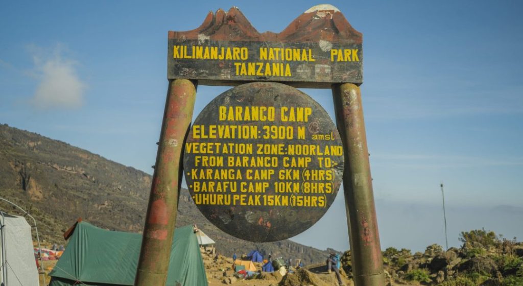 Signpost at Barranco Camp in Kilimanjaro National Park showing an elevation of 3,900 meters above sea level, with distances to Karanga Camp, Barafu Camp, and Uhuru Peak.