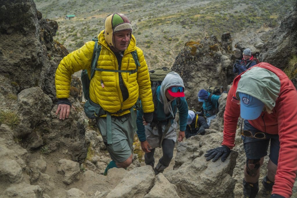 Trekkers climbing the Barranco Wall on Mount Kilimanjaro with guidance mountain crew.