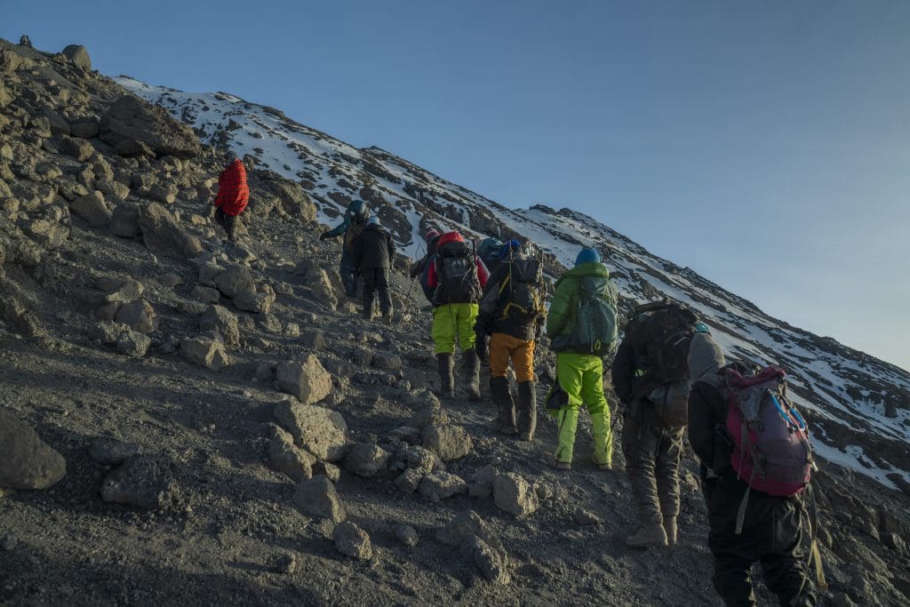 Climbers ascending a steep volcanic slope on Mount Kilimanjaro near the arctic zone during summit push.