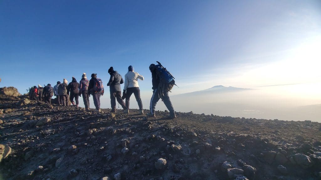 Hikers ascending Mount Meru summit ridge during early morning trek above the clouds