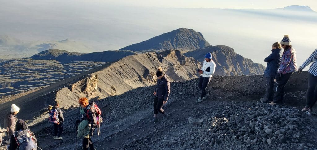 Hikers descending Mount Meru volcanic ridge with panoramic views inside Arusha National Park