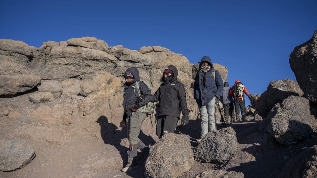 Climbers trekking through rocky terrain on Mount Kilimanjaro during the final ascent