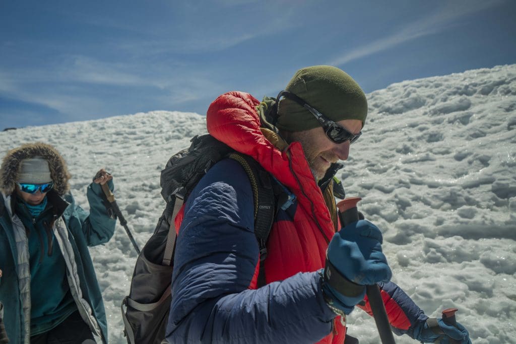 Climbers crossing snow and ice near the summit of Mount Kilimanjaro in December wearing insulated jackets, gloves, and sunglasses.